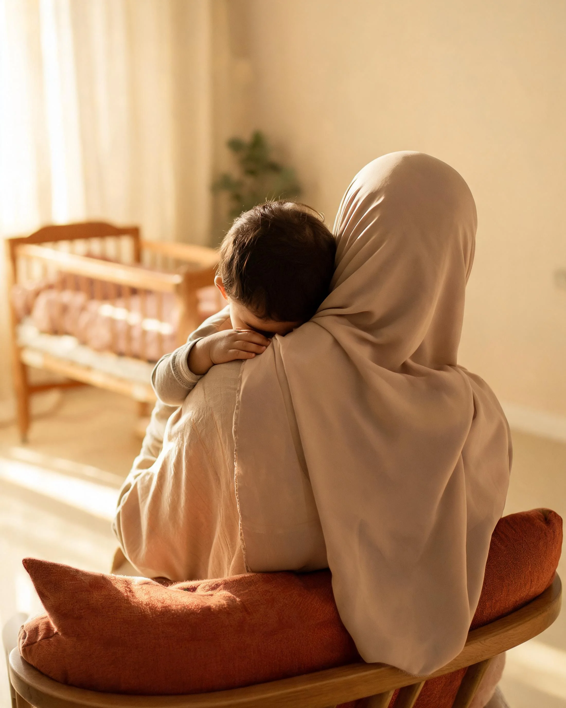 A mother holding her child by a window in warm light